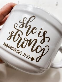 someone holding a coffee mug with the words she's strong on it in brown ink