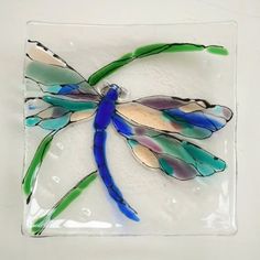 a glass dragonfly sitting on top of a white surface