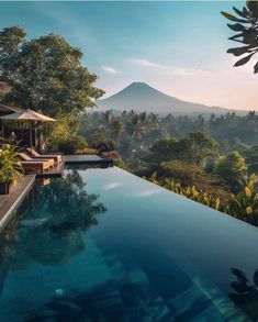 an outdoor swimming pool surrounded by trees and mountains