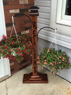 two hanging planters with flowers in them on the front steps of a house next to a window