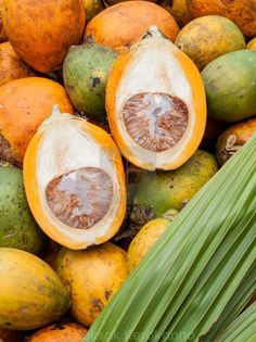 a pile of fruit that is sitting on top of each other with green leaves next to it