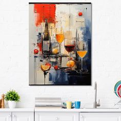 a painting hanging on the wall above a kitchen counter with wine glasses and oranges