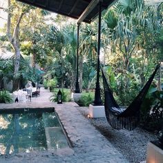 an outdoor dining area with hammock chairs and tables next to a swimming pool