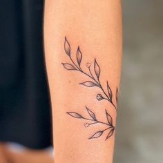 a woman's arm with a tattoo on it that has leaves and dots all over it