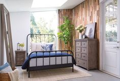 a bed room with a neatly made bed next to a wooden dresser and window sill