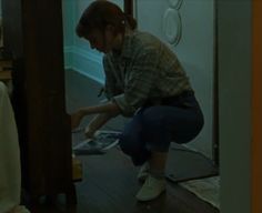 a woman kneeling down on the floor in front of a door