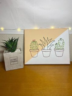 two potted plants sitting on top of a wooden table next to a white box