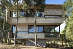 the house is made out of wood and has many windows on each floor, along with stairs that lead up to the second floor