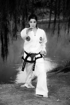 black and white photograph of a woman in karate gear standing by a river with her hand on her hip