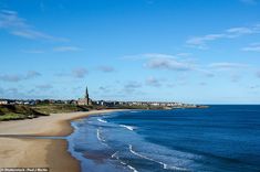 the beach is empty and blue with waves coming in from the water, on a sunny day