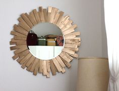 a mirror sitting on top of a wooden table next to a lamp and a vase