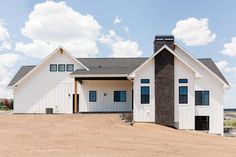 a large white house sitting on top of a dirt field