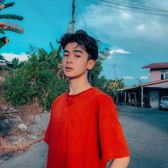 a young man standing on the side of a road in front of a palm tree