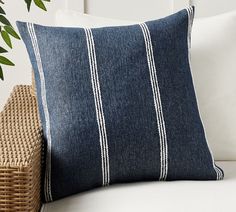 a blue and white pillow sitting on top of a couch next to a wicker basket