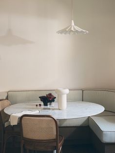 a white table with two chairs and a vase on it next to a light fixture