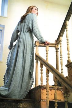 a woman in a long dress is standing on the stairs