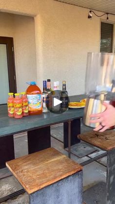 a person is pouring something into a can on top of a table with two stools