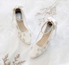 two pairs of white shoes with bows on them