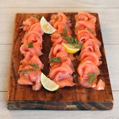 salmon on a wooden cutting board with lemon wedges