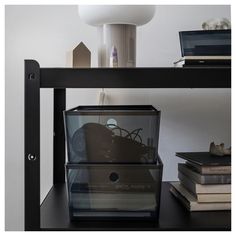 there is a glass box on top of the table next to books and a lamp