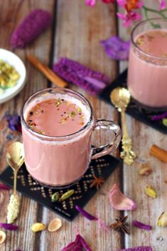 two mugs filled with pink liquid sitting on top of a wooden table