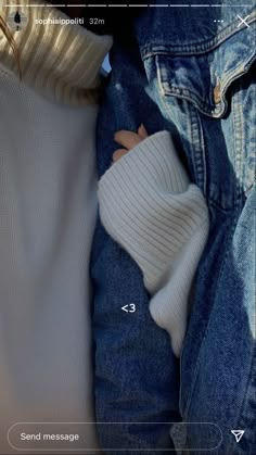 a baby wrapped in a white blanket next to a pair of blue jeans and a denim jacket