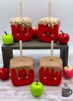 some apples are sitting on a table with sticks sticking out of them