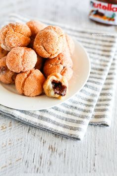 a white plate topped with pastries on top of a striped cloth next to a jar of peanut butter