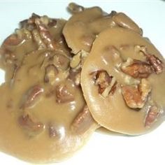 three biscuits covered in gravy sitting on top of a white plate with pecans