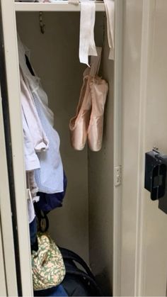 there is a closet with clothes and shoes hanging on the door handle, next to an open suitcase