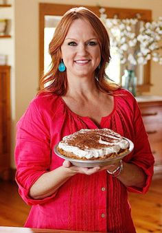 a woman holding a pie on top of a wooden table