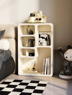 a white book shelf sitting on top of a bed next to a black and white checkered rug