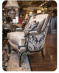 an ornate chair and ottoman in a large room with wood floors, chandeliers and lamps