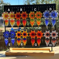 an assortment of beaded earrings are displayed on a stand in front of a fence