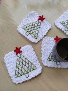 four crocheted coasters with christmas trees on them and a coffee cup in the middle