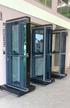 three black and silver portable toilets sitting next to each other in a room with windows