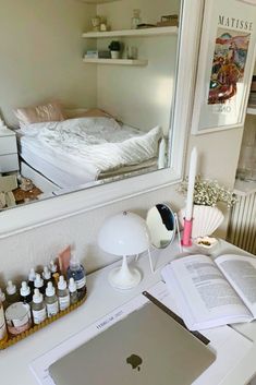 an apple laptop sitting on top of a desk in front of a mirror and books