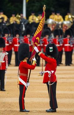 two men in red uniforms are holding a flag