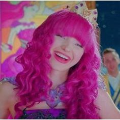 a girl with pink hair wearing a tiara and smiling at someone in the background