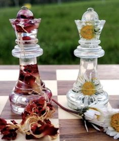 two glass chess pieces with flowers in them