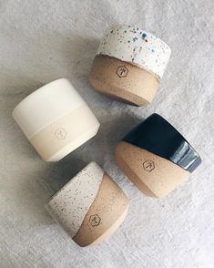 four ceramic cups sitting on top of a white tablecloth covered floor with confetti sprinkles