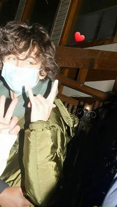 a person wearing a face mask and making the peace sign