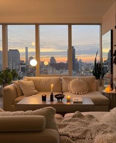 a living room filled with furniture and large windows overlooking the cityscape at sunset