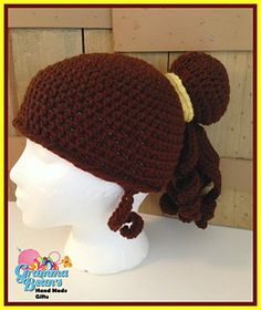 a crocheted hat with two pompons on it, sitting on a mannequin head