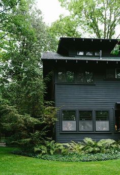 a black house with lots of windows and trees