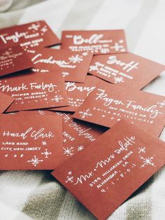 six red business cards with white ink on them sitting on a bed covered in blankets