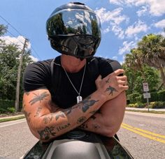 a man with tattoos on his arm sitting on top of a motorcycle