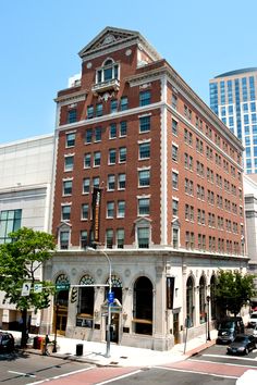 an old brick building on the corner of a street in front of some tall buildings