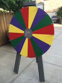 a large colorful wheel on top of a metal stand in front of a fenced yard