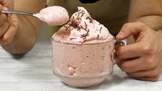 a person holding a spoon over a cup filled with ice cream